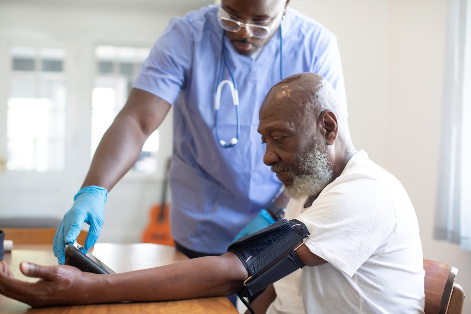 A clinician checking blood pressure for a patient during an in-home visit